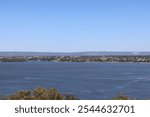 wide-angle landscape large deep blue water bay with distant urban shoreline and rolling hills