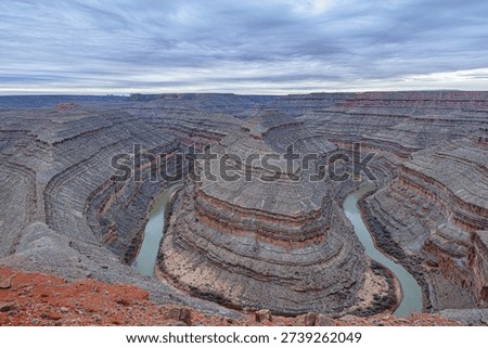 A wide-angle, panoramic view of the deep, winding entrenched meanders of the San Juan River carved into the desert landscape at Goosenecks State Park