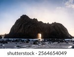 Wide-angle shot of the keyhole arch at Pfeiffer beach, California, whit the setting sun peeping through the central hole. Sunset on a winter evening in California.