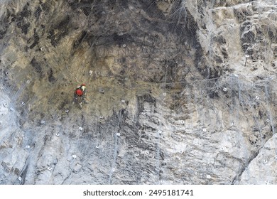 A wide-angle stock photo of a professional climber scaling a challenging cliff with full gear. The image captures determination and skill, perfect for adding text. Ideal for adventure and outdoor - Powered by Shutterstock