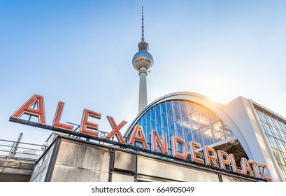 Wide-angle view of Alexanderplatz neon sign with famous TV tower and train station in golden evening light at sunset in summer, central Berlin Mitte district, Germany