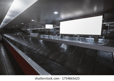 Wide-angle View Of A Baggage Claim Area In A Hall Of A Modern Airport Arrival Zone With Luggage Conveyor Belt And A Mock-up Of White Empty Advertising Or Information Billboard And Tv Plasma Screen