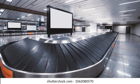 Wide-angle View Of An Empty Luggage Conveyor Belt With The Rubber Sections And Blank White LCD Informational Screen Mockup On The Top And Behind; Bright Arrival Zone Of A Contemporary Airport Terminal