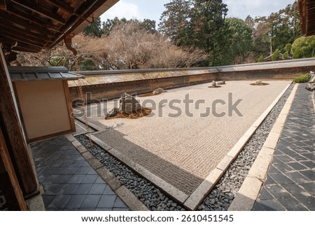 Wide-angle view of the iconic Zen rock garden at Ryoanji Temple in Kyoto, Japan. Carefully raked gravel and strategic stone placement create a serene space for meditation.
