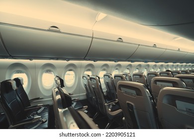 A wide-angle view of a long cabin of a passenger plane with empty rows of plastic seats in economy class of the airplane with safety instructions in the pockets on the other sides of them - Shutterstock ID 2203905121