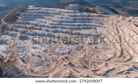 A wide-angle view of the massive marble quarry in Burdur. The terraced system on the mountainside and the orderly arrangement of the marble blocks are striking.