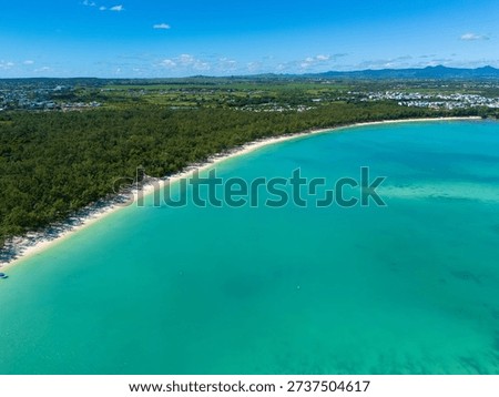 Wide-angle view of a pristine tropical beach in Mauritius, featuring soft golden sand, swaying palm trees, and calm turquoise waters under a dramatic cloudy sky. A serene Indian Ocean coastline perfect for travel, relaxation, and island getaway concepts.

