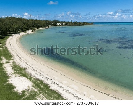 Wide-angle view of a pristine tropical beach in Mauritius, featuring soft golden sand, swaying palm trees, and calm turquoise waters under a dramatic cloudy sky. A serene Indian Ocean coastline perfect for travel, relaxation, and island getaway concepts.
