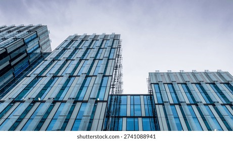 Wide-angle view of the repeating patterns and geometric glass panels of a modern corporate high-rise building in an urban setting in Manchester.