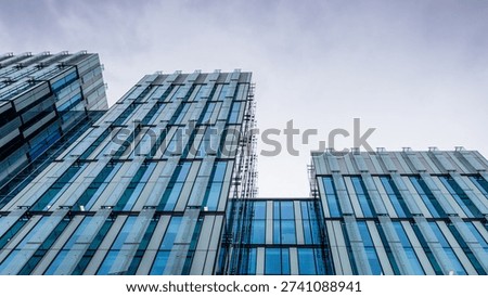Wide-angle view of the repeating patterns and geometric glass panels of a modern corporate high-rise building in an urban setting in Manchester.