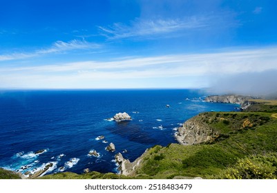 Wide-angle view of a stunning Pacific Ocean beach near Highway 101 in the San Francisco Bay Area, featuring vibrant rock formations, lush green grass, and a brilliantly blue ocean. - Powered by Shutterstock