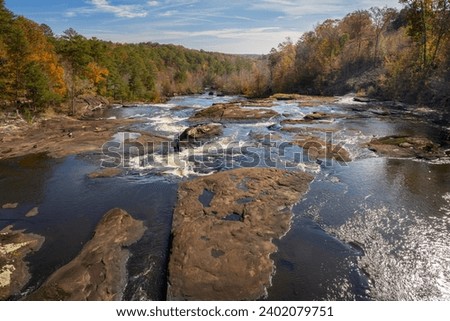 A wide-angle view of the Towaliga River cascading over granite rock outcrops as it flows downstream - photographed in Fall from the High Falls Road Bridge in High Falls State Park, Jackson, Georgia. 