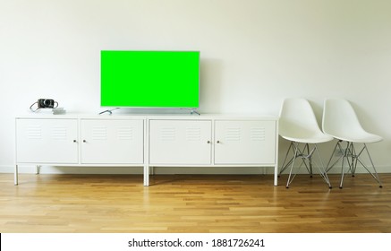 Widescreen Modern Green Screen TV For Text And Video On A Chrome Stand Against A White Wall.	