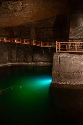WIELICZKA, POLAND - JUNE 30: Underground Staircase And Wieliczka Salt Cave Lake. Interior View Of Wieliczka And Bochnia Royal Salt Mines Textured Salt Walls And Ceiling, Dimly Lit By Artificial Lights