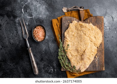 Wiener breaded raw pork Schnitzel, meat steak on a wooden board. black background. top view.