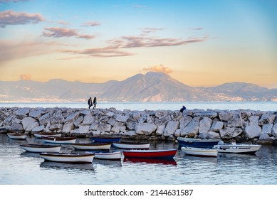 Wiew over fish boats embarked in the bay of Napoli on a gloomy spring evening. Napoli waterfront with Napoli hills and buildings on the background. Italy - Shutterstock ID 2144631587