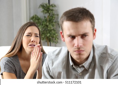 Wife asking for forgiveness to her ex husband after conflict sitting on a couch in the living room of a house