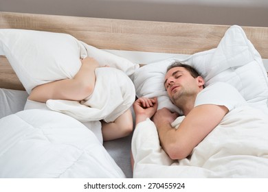 Wife Covering Ears From Cushion While Husband Snoring In Bedroom