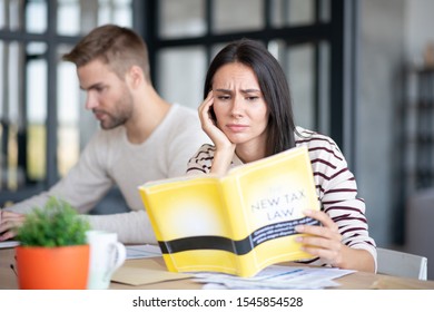 Wife Feeling Confused. Beautiful Dark-haired Wife Feeling Confused While Reading Book About New Tax Law