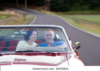 A wife looks at her husband with love as they drive their vintage red convertible down a country road. Subjects are placed in the lower corner to allow room for text. - Powered by Shutterstock