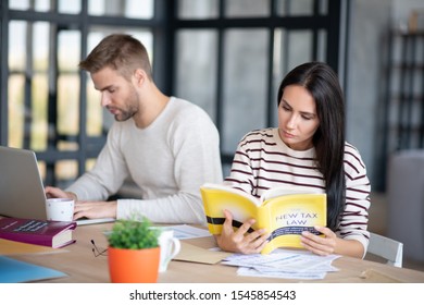 Wife Reading. Smart Dark-haired Wife Reading New Tax Law While Husband Working On Laptop