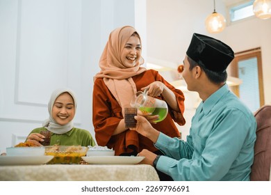 wife serves drink to husband while breaking fast at the dining table - Powered by Shutterstock