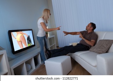 Wife Standing Blocking The Television Set And Preventing Her Husband From Watching Female TV While Remonstrating With Him