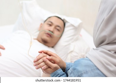 Wife Takes And Holds Hand Of Her Husband Who Is Sick And Sleep On Bed In Hospital, Sad Emotional Moments, Focus On Hands With Blurry Face