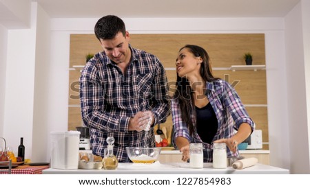 Wife teasing her husband while he's trying to cook for her. Happy couple