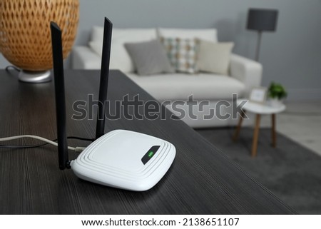 Wi-Fi router on black wooden table in room. Space for text