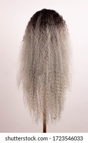 Wig curly gray long hair on a mannequin on a white background