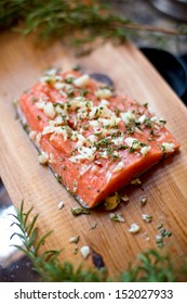 Wild Alaskan Salmon Fillet On A Cedar Plank That Is Ready To Be Grilled.  It's Seasoned With Garlic, Rosemary, Salt And Pepper.