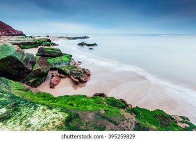 Wild beach and red rock cliffs in famous heritage site Jurassic Coast in UK