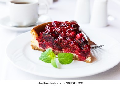 Wild berries cake with green mint on plate with fork. Selective focus