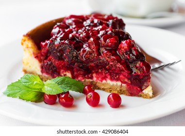 Wild berries cake with green mint on plate with fork. Selective focus