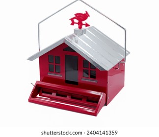 wild bird feeder with metal tin aluminum roof with built in anti squirrel buster bar.  In shape of old classic red barn with rooster wind weather vane ornament on top isolated on white background