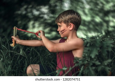 Wild boy playing outside with a slingshot