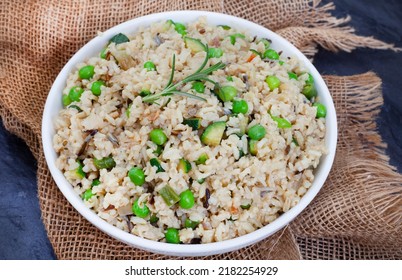 Wild And Brown Rice Pilaf With Green Peas, Onion And Baby Marrow On Black Slate With Burlap And Copy Space