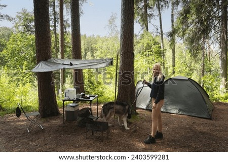 Wild camping in nature in summer. A girl near a tent with a husky dog. High quality photo