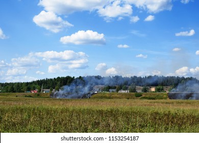 Wild Fire And Smoke In Dry Meadow Grass Due To Hot Windy Weather In Summer Started To Burn From Railway Behind And Two Firefighters. Firefighting Rescue Operation Concept.
