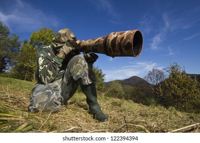 Wild Life Photographer With Long Telephoto Lens In Action Dress Of Camouflage