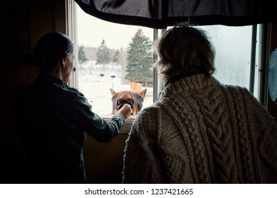 Wild Mountain Farm , Canning , Nova Scotia / Canada - DEC 31 2017 : Two Woman Playing And Feeding A Horse From Inside Their Home Through A Window During Winter