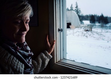 Wild Mountain Farm , Canning , Nova Scotia / Canada - DEC 31 2017 : Woman Looking From Inside Her Home Through A Window During Winter