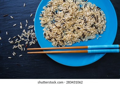 wild rice in ceramic bowl and chopsticks on wooden background