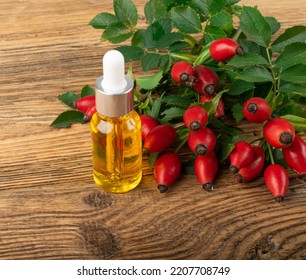 Wild Rose Essential Oil. Rose Hip Extract, Rosehip Extraction, Dog Rose Infusion, Dogrose Oil On Wood Background