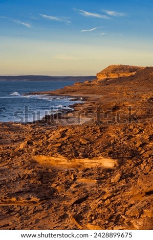 The wild, sandstone coast near Mushroom Rock, Kalbarri National Park, Western Australia. The red sandstone lights a sunset
