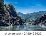 Wild and scenic Rogue River in Southern Oregon with a distant rafter floating. 