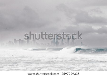 Wild surf with breaking waves and a threatening, overcast sky over the skyscrapers of Surfers Paradise as a tropical cyclone or hurricane approaches the Gold Coast in Queensland, Australia.