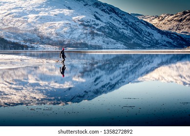 Wild Swim Woman In Wetsuit Walks Into Water With Snow On Mountains Reflected 