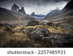 Wild Weasel river winds through remote arctic valley of Akshayuk Pass, Baffin Island, Canada on a cloudy day. Dramatic arctic landscape with Mt. Breidablik and Mt. Thor. Autumn colors in the arctic